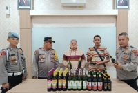 WS (63 thn) beserta puluhan botol miras, berhasil diamankan di Mapolsek  Prigen (foto: ist)